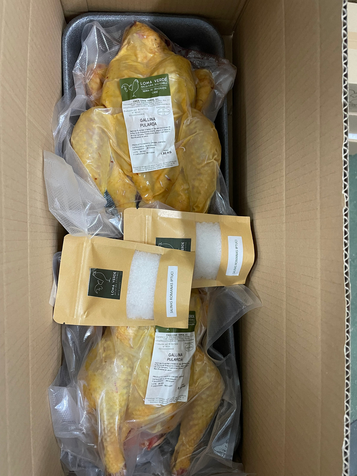 Dos pulardas Loma Verde evisceradas, envasadas al vacío y etiquetadas con su peso, en la caja de envío
